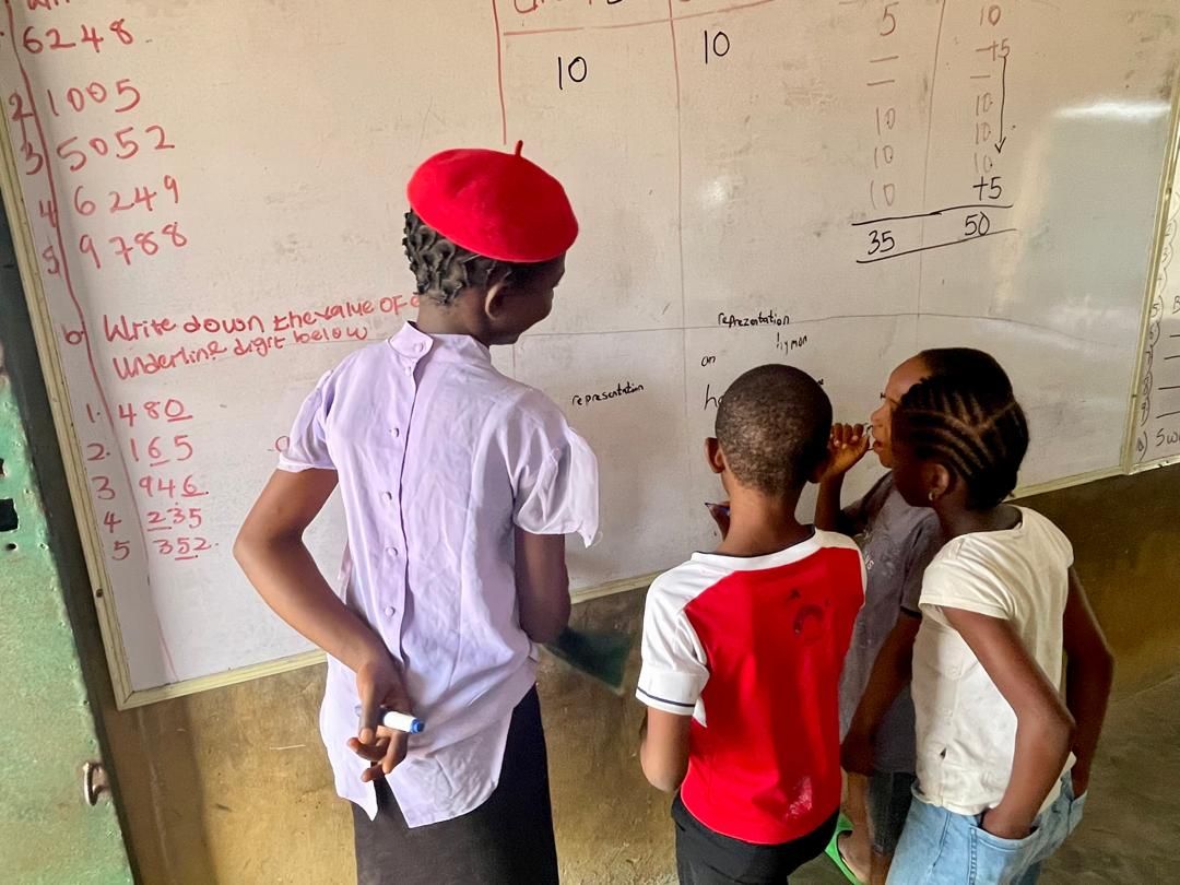 A young volunteer leading a maths lesson for children